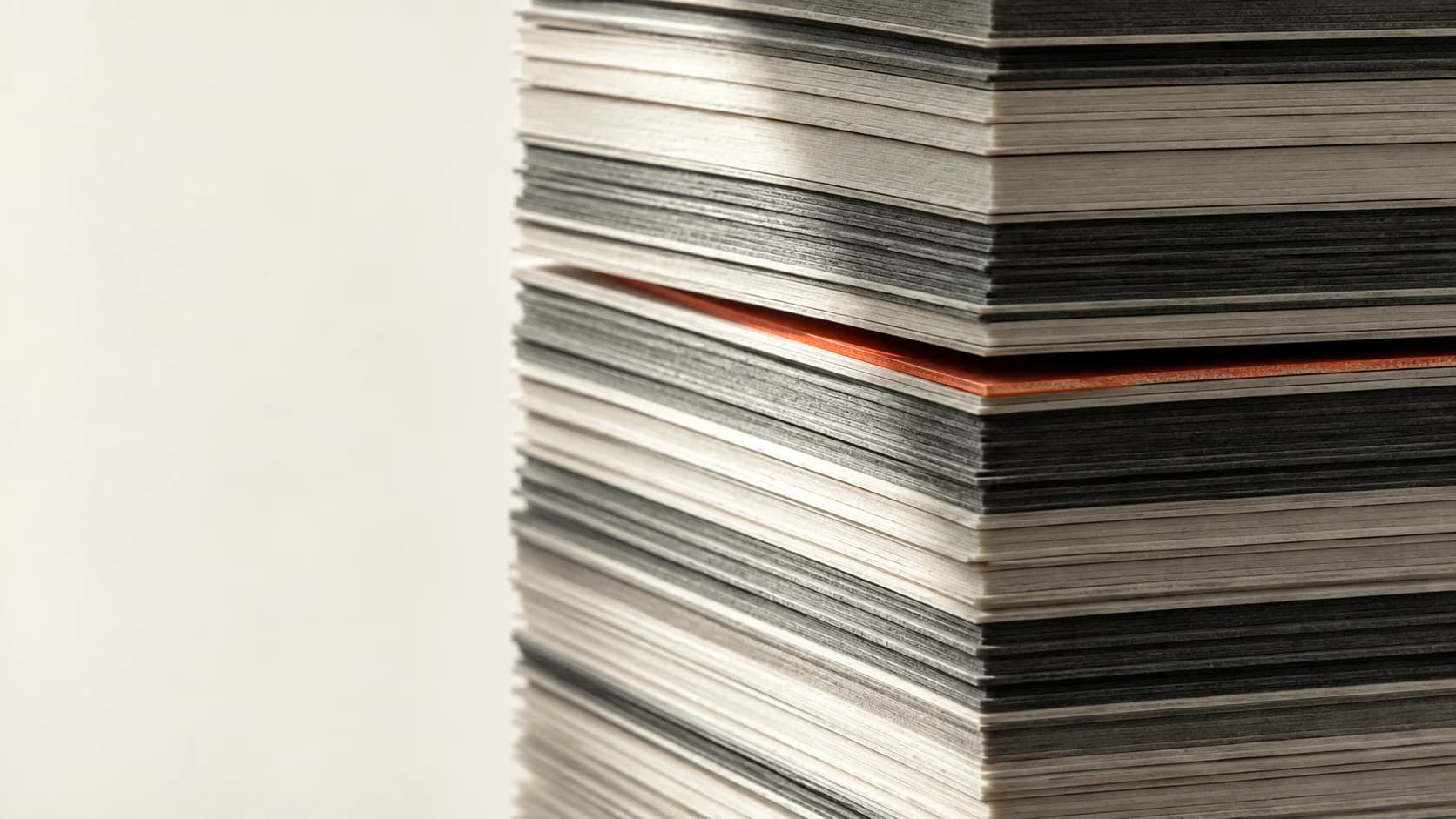 A displaced layer reveals an orange edge within precisely aligned sheets: an editorial study of discovery.