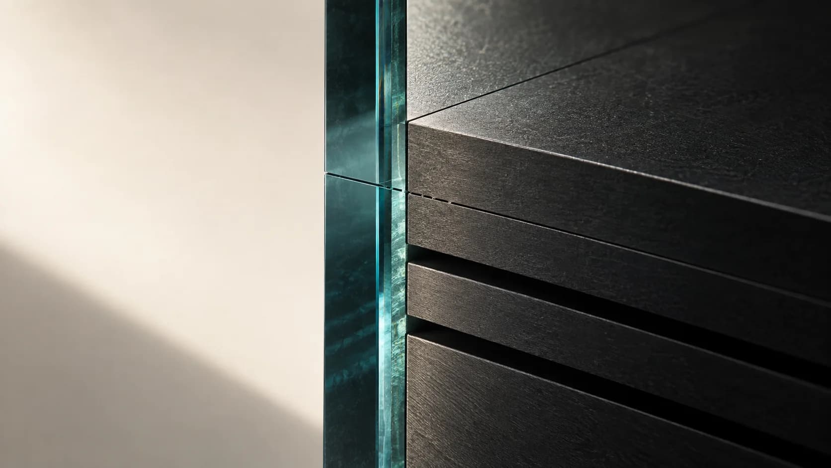 Graphite planes meet a precise teal glass boundary against an open ivory field.